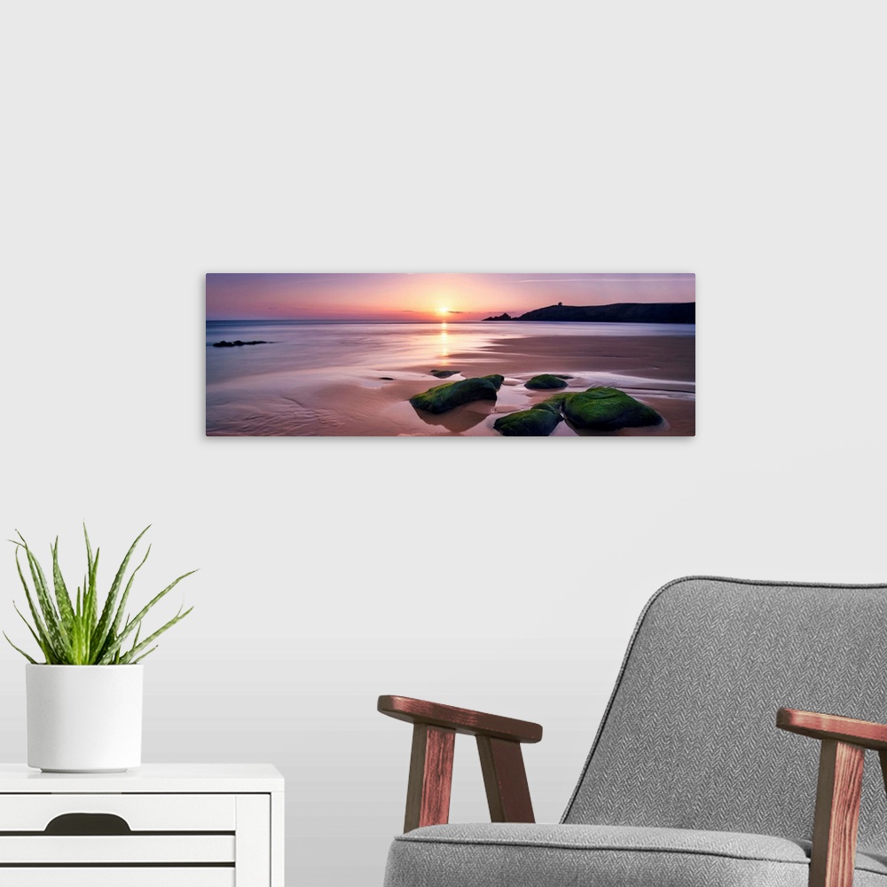 A modern room featuring Panoramic beach with rocks during a pink quite sunset in Brittany, France.