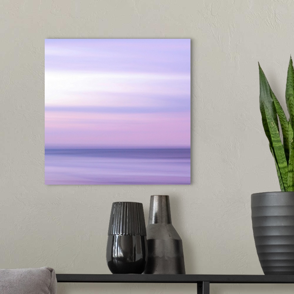A modern room featuring Abstract artwork of a sunset sky over the ocean with a haze over the entire piece to give it a so...