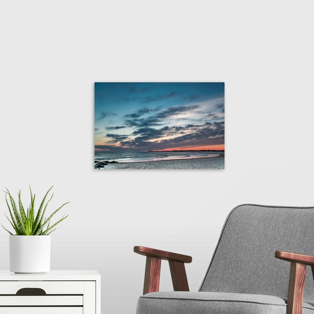 A modern room featuring Cloudy skies at sunset over a sandy beach.