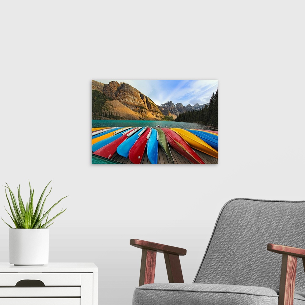 A modern room featuring Large, horizontal photograph of colorful boats lined up on a dock at Moraine Lake.  The mountains...
