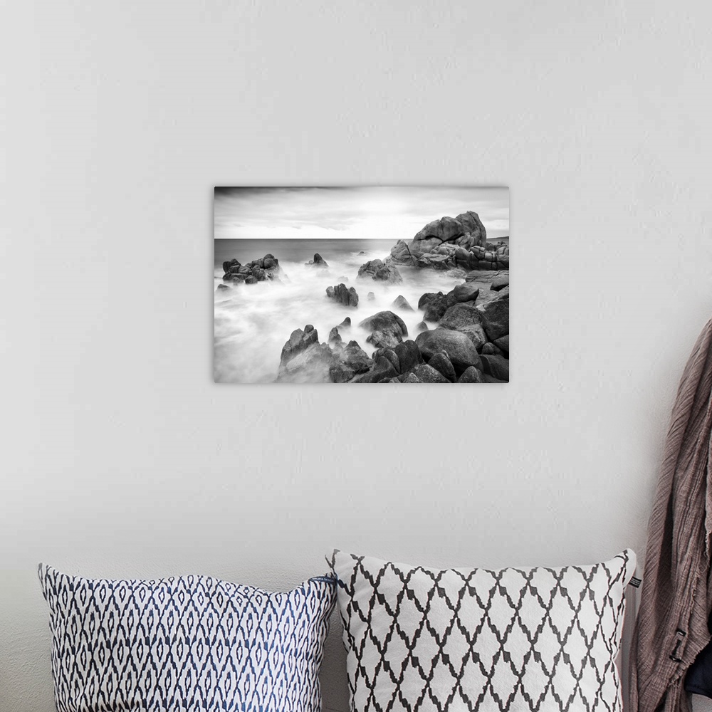 A bohemian room featuring A black and white photograph of a rocky coastline.