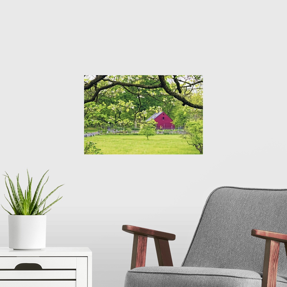 A modern room featuring A photograph of a countryside scene with a red barn seen in the distance.