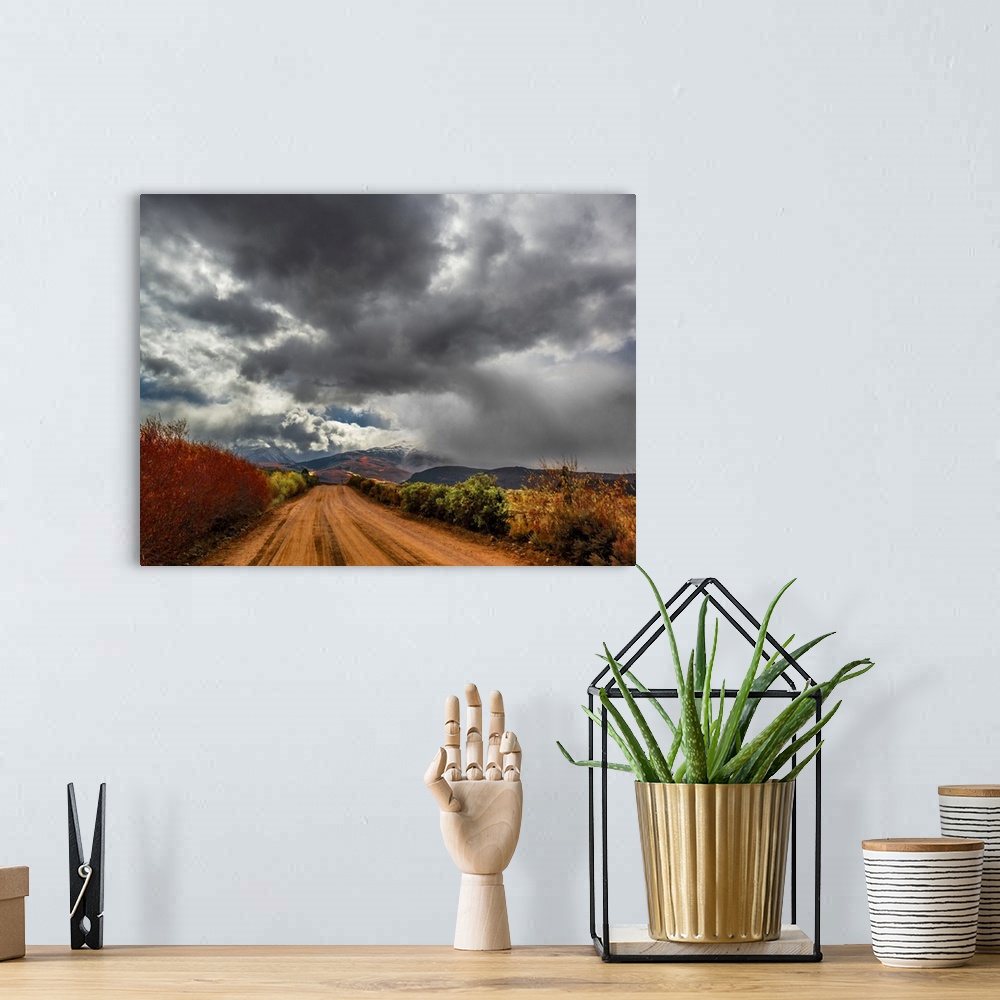 A bohemian room featuring Dark storm clouds over a dirt road in the countryside.