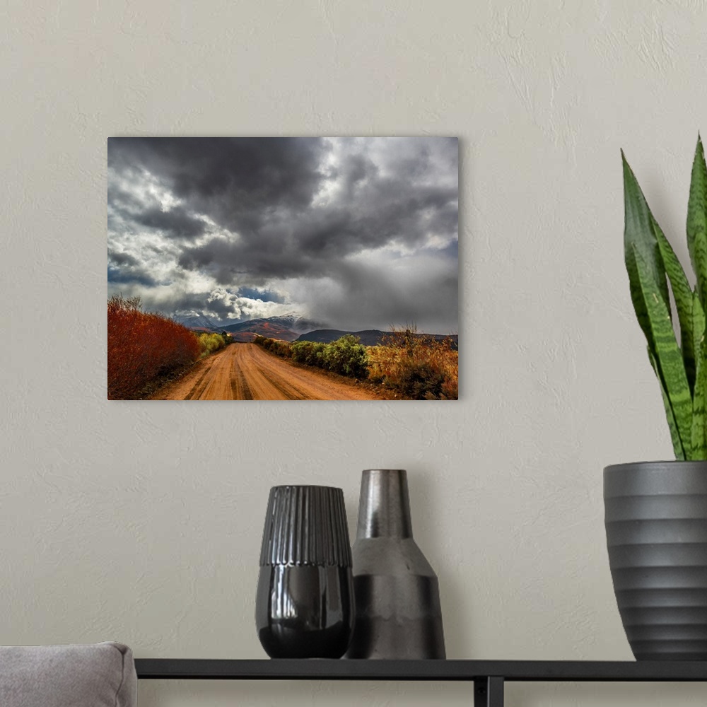 A modern room featuring Dark storm clouds over a dirt road in the countryside.