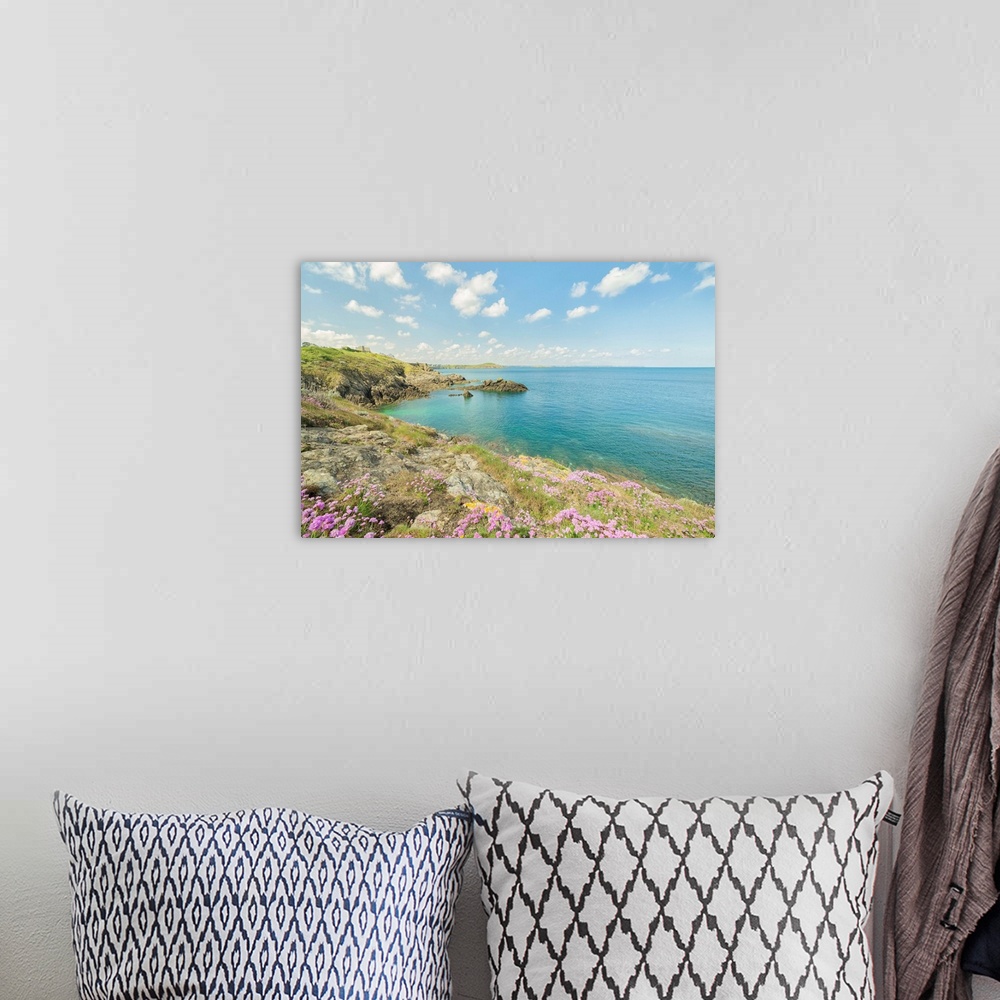 A bohemian room featuring Pink flowers on the coast of St. Lunaire in northern France, overlooking a turquoise ocean.