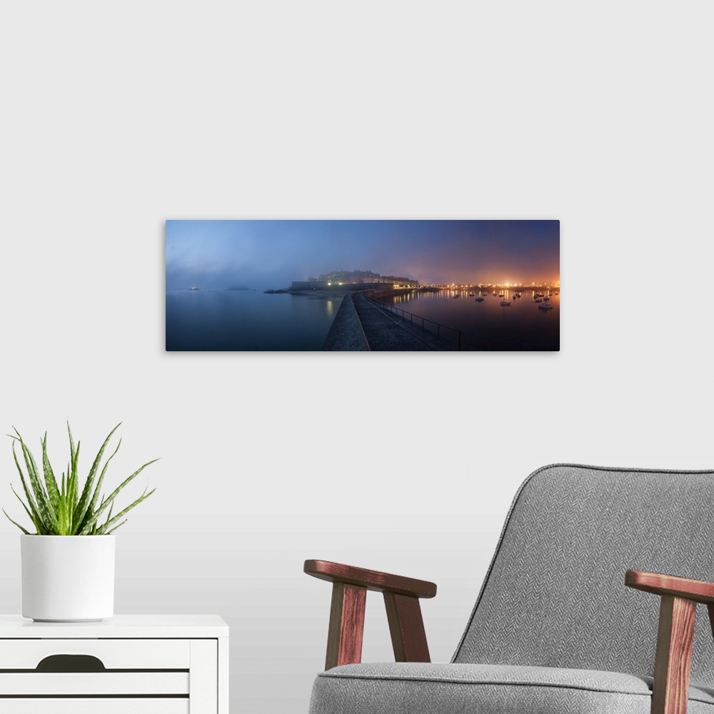 A modern room featuring Panoramic view of Saint Malo city in Brittany at night with fog coming from the sea, blue and pin...