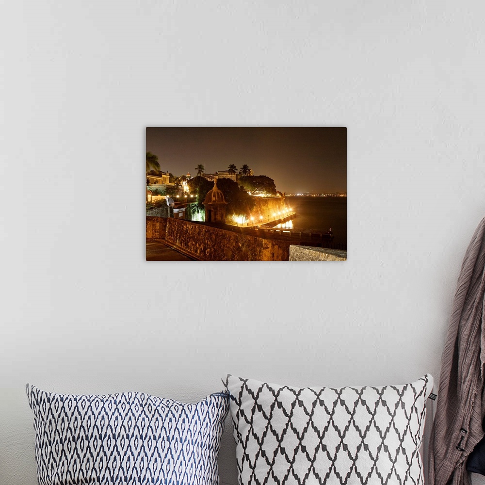 A bohemian room featuring Large photograph taken at nighttime focuses on a section of an illuminated shoreline within the c...