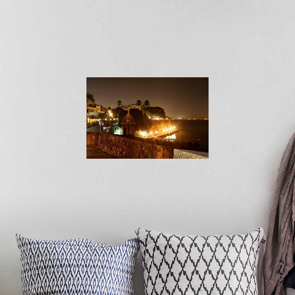 A bohemian room featuring Large photograph taken at nighttime focuses on a section of an illuminated shoreline within the c...