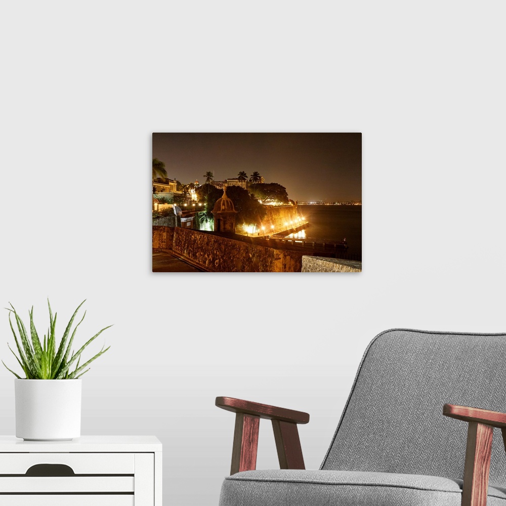 A modern room featuring Large photograph taken at nighttime focuses on a section of an illuminated shoreline within the c...