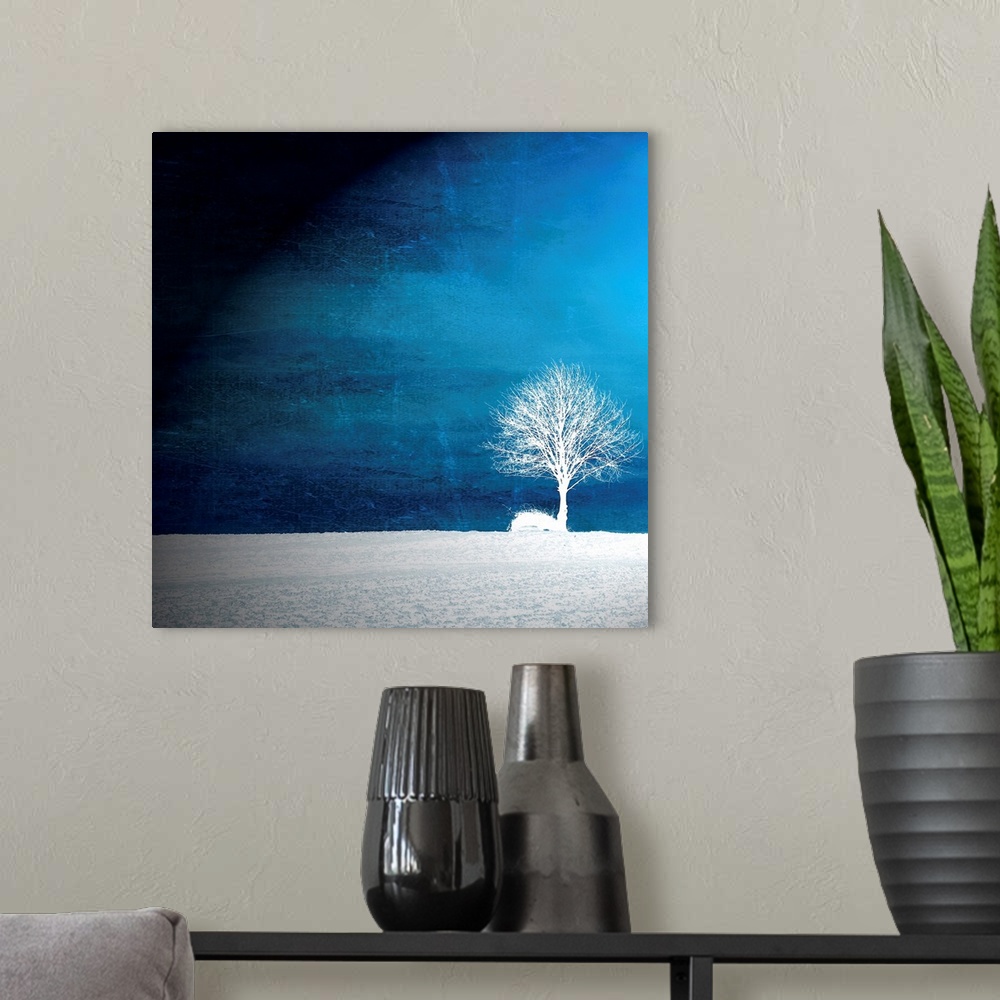 A modern room featuring This oversize piece shows a single tree in white sitting in a bare field with a vibrant blue sky ...
