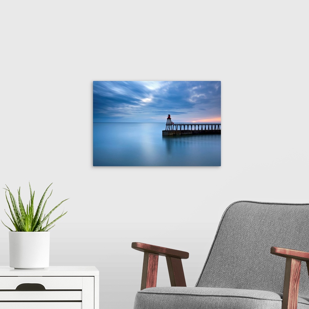 A modern room featuring Timeless blue dawn over flat sea with scudding clouds and a lighthouse jetty.