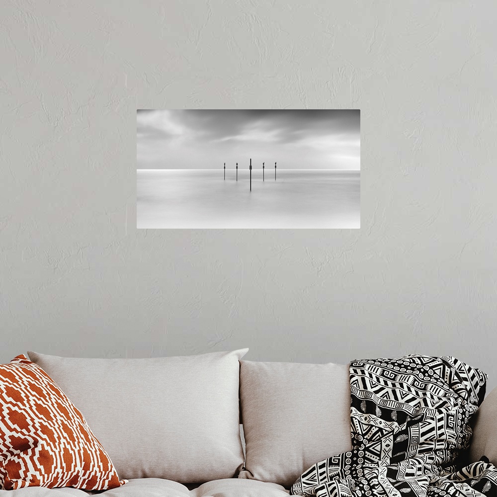A bohemian room featuring Minimal panoramic monochrome black and white zen calm seascape with five poles in the flat sea.