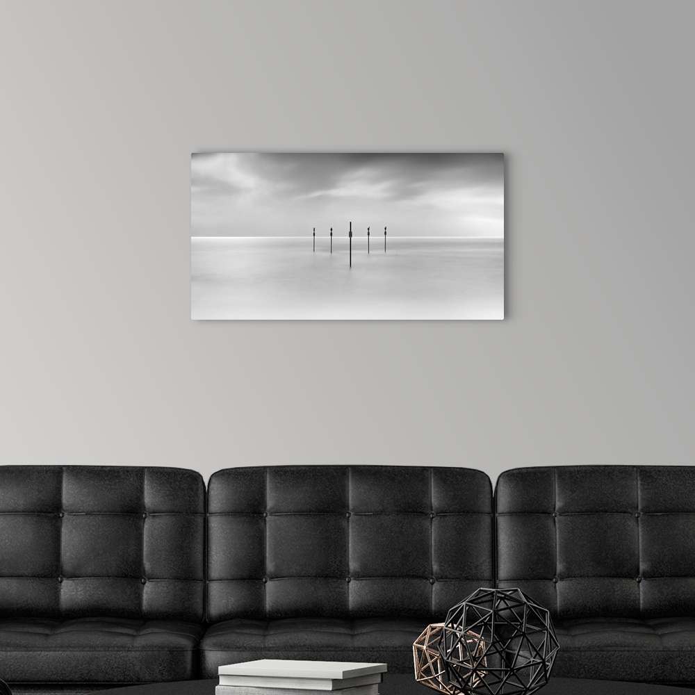 A modern room featuring Minimal panoramic monochrome black and white zen calm seascape with five poles in the flat sea.