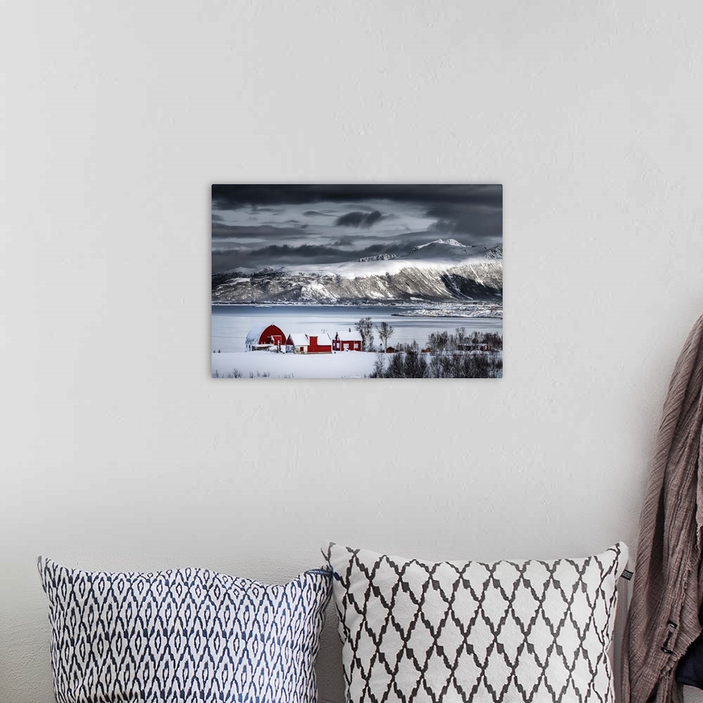 A bohemian room featuring A photograph of a red building sitting on the shoreline of a snowy landscape with mountains in th...