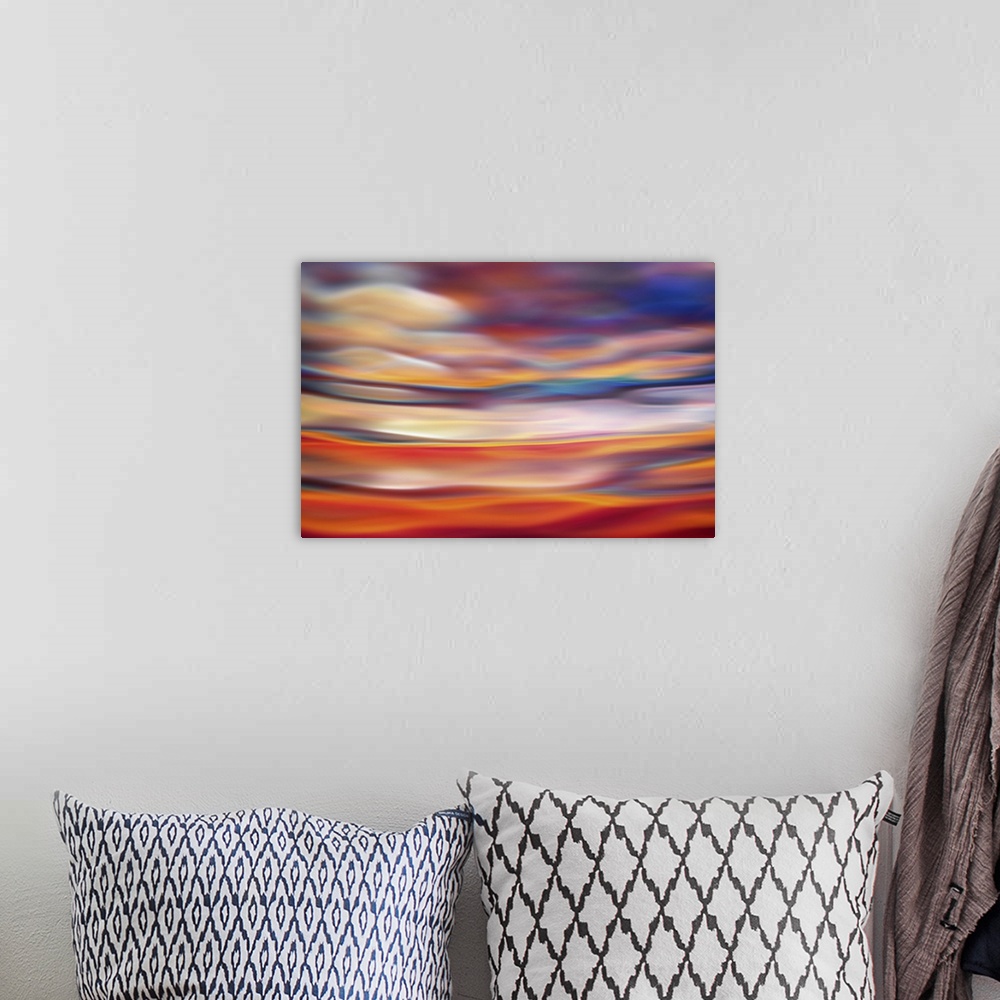 A bohemian room featuring Abstract photograph in orange and red shades resembling ocean waves.