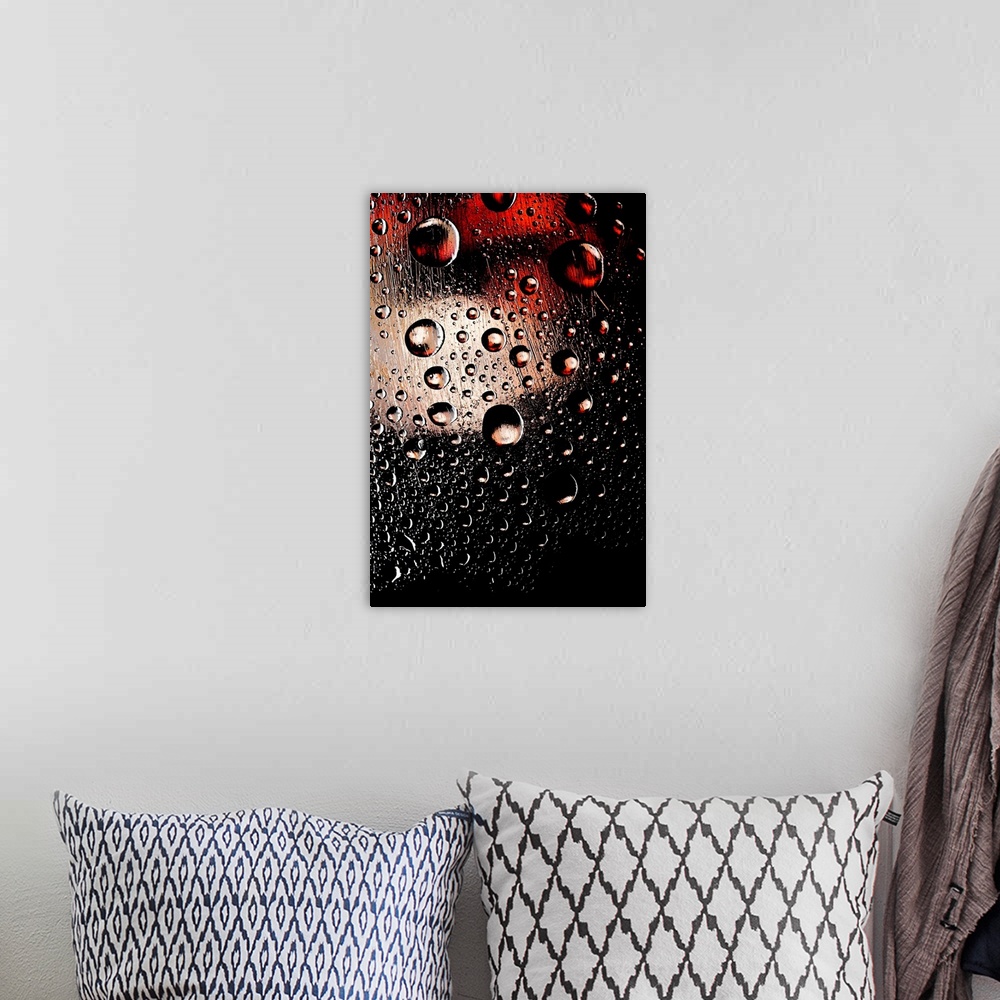 A bohemian room featuring A photo of raindrops sitting on a window with red and white lights shining behind.