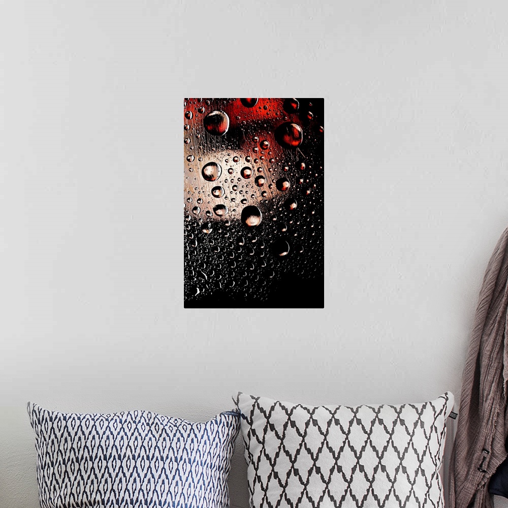 A bohemian room featuring A photo of raindrops sitting on a window with red and white lights shining behind.