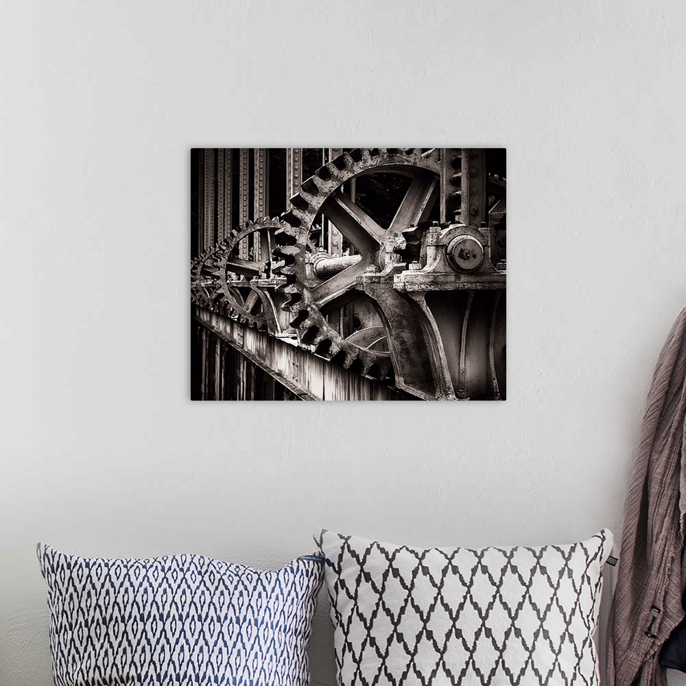 A bohemian room featuring A photograph of a set of large old looking gears that operate a gate.