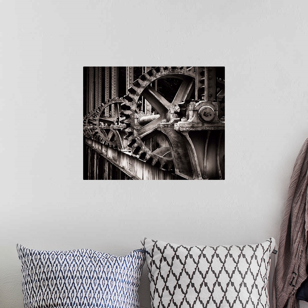 A bohemian room featuring A photograph of a set of large old looking gears that operate a gate.