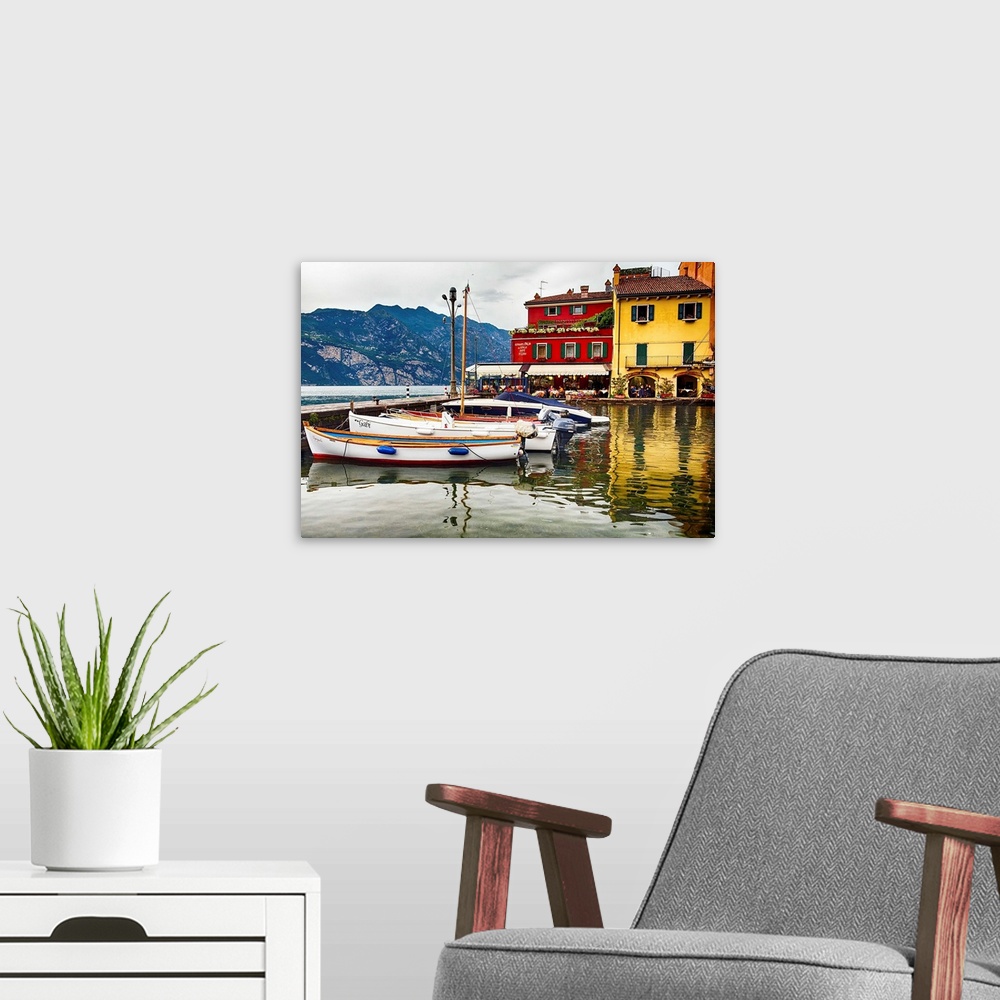 A modern room featuring Fine art photo of boats docked in a harbor near brightly painted houses in Italy.