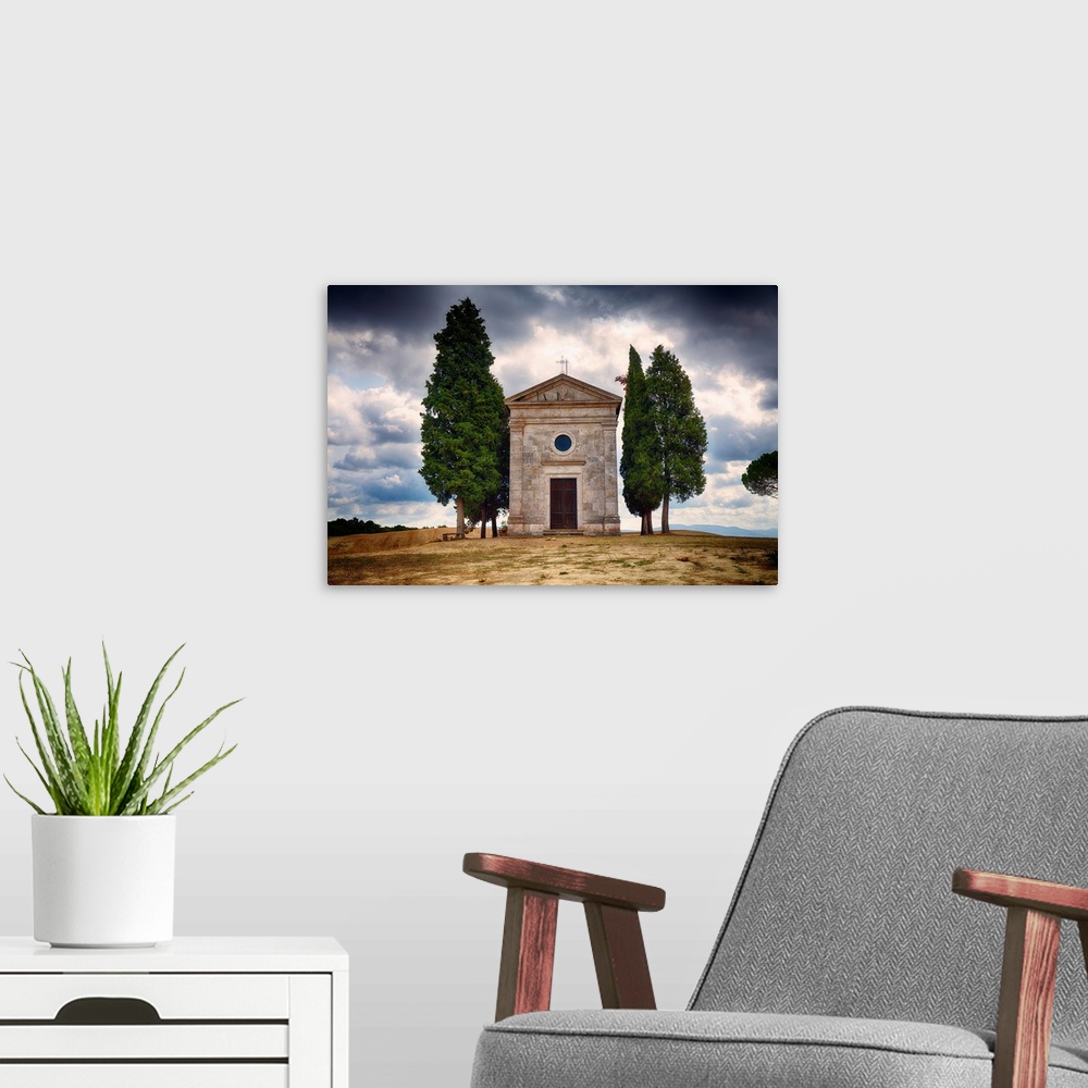 A modern room featuring A photograph of a small chapel with a backdrop of a Tuscan landscape against rolling clouds.