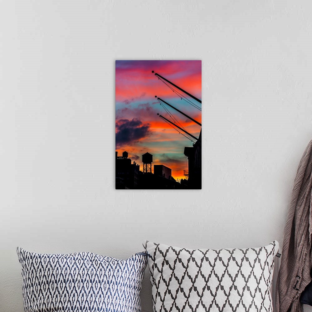 A bohemian room featuring Silhouetted water tower and cranes against a vivid red and orange sunset sky.