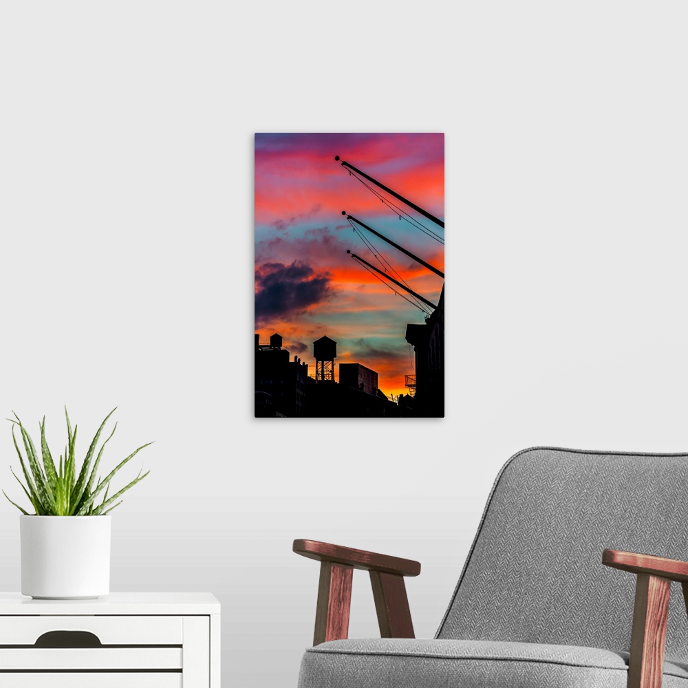 A modern room featuring Silhouetted water tower and cranes against a vivid red and orange sunset sky.
