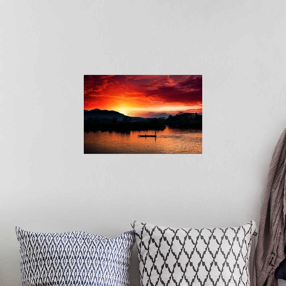 A bohemian room featuring Red sunset over the Mekong with a boat in the foreground