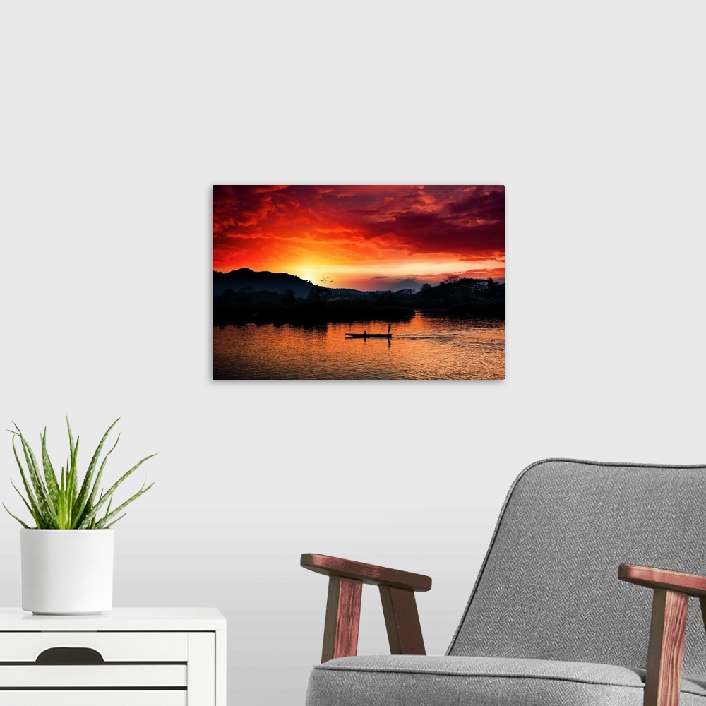A modern room featuring Red sunset over the Mekong with a boat in the foreground