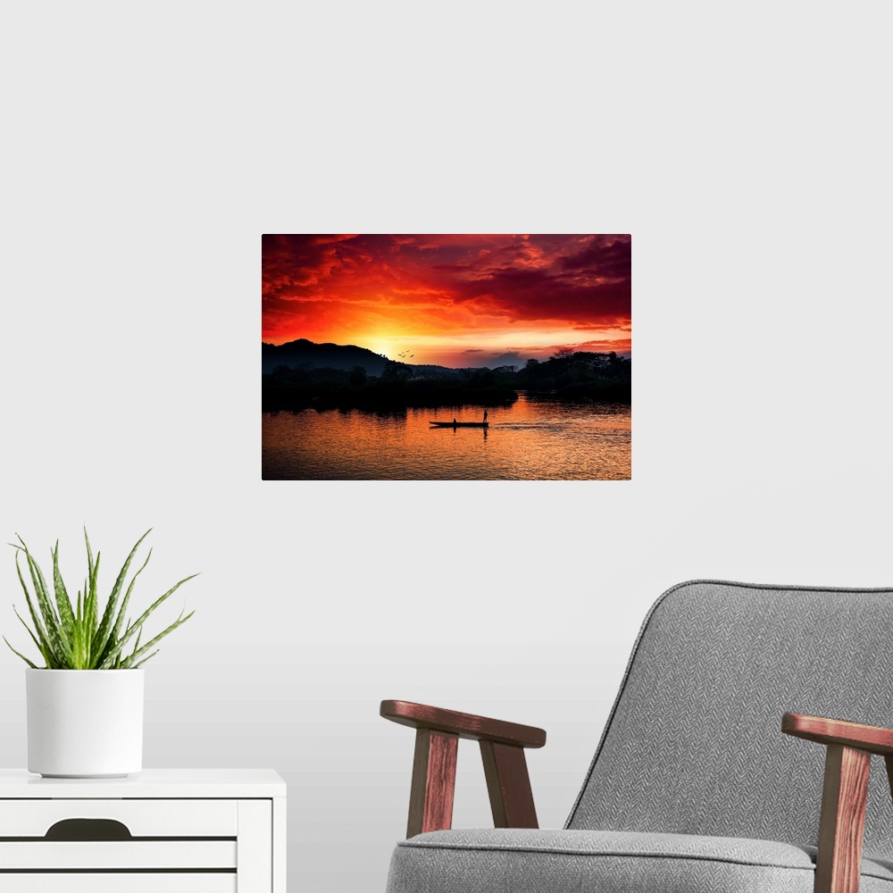 A modern room featuring Red sunset over the Mekong with a boat in the foreground