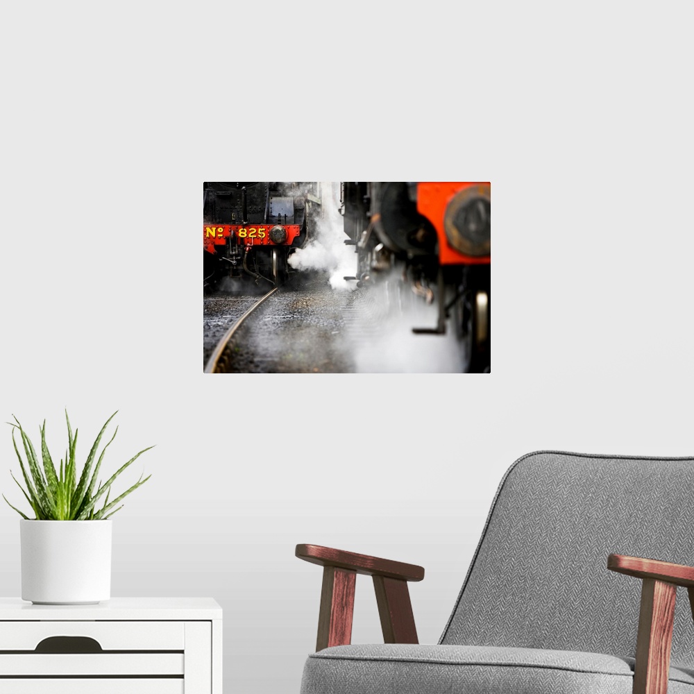 A modern room featuring This wall art piece depicts the front of two trains, one up close and one further back, both with...