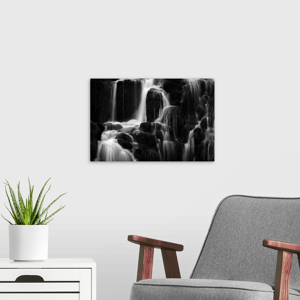 A modern room featuring Fine art photo of a waterfall over several round rocks in black and white.
