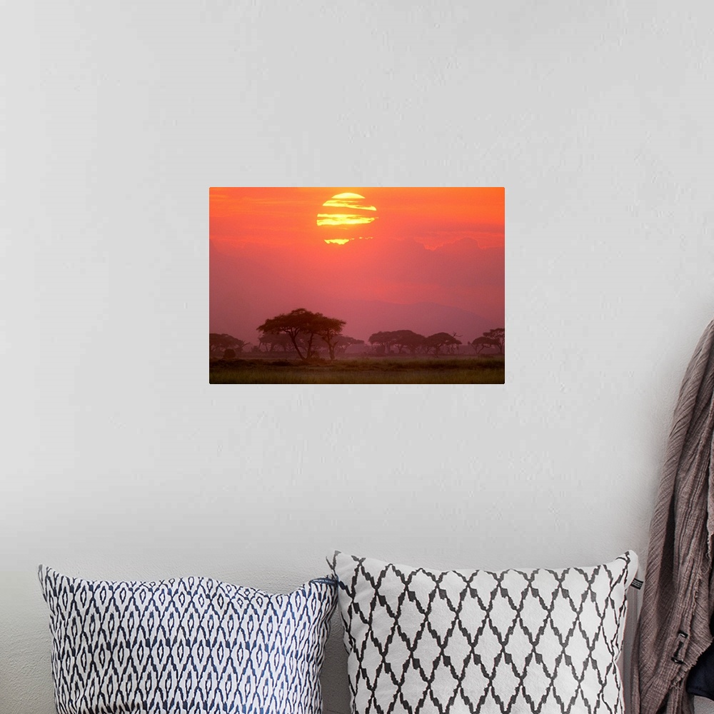 A bohemian room featuring Landscape photograph of the sun setting behind streaky clouds, over a Savanna landscape or grasse...