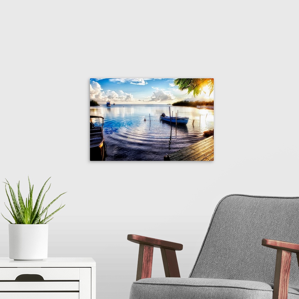 A modern room featuring Huge photograph includes a number of boats sitting within a bay of a tropical island as the sun b...