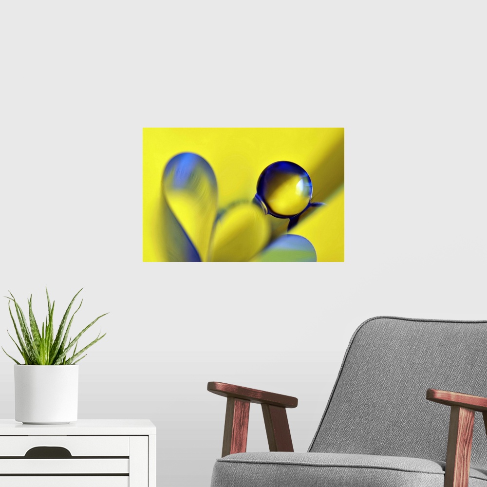 A modern room featuring Macro abstract photograph of a water droplet reflecting on a yellow surface with blue ribbon-like...