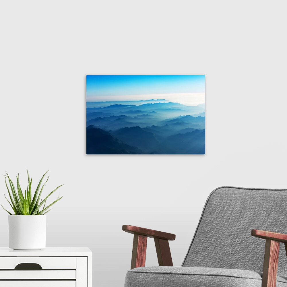 A modern room featuring Mountains of Laos seen from the sky in a bluish atmosphere at sunrise