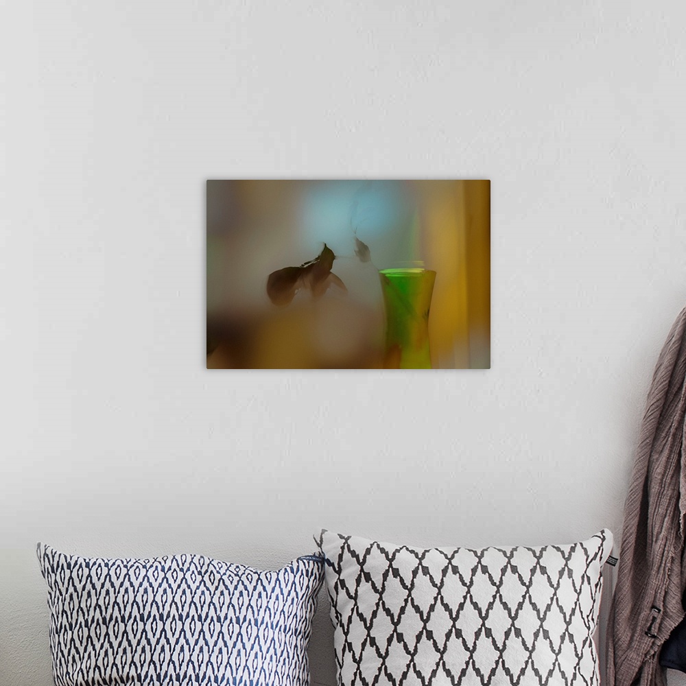 A bohemian room featuring A soft of focus photo of a dying plant inside a vase.