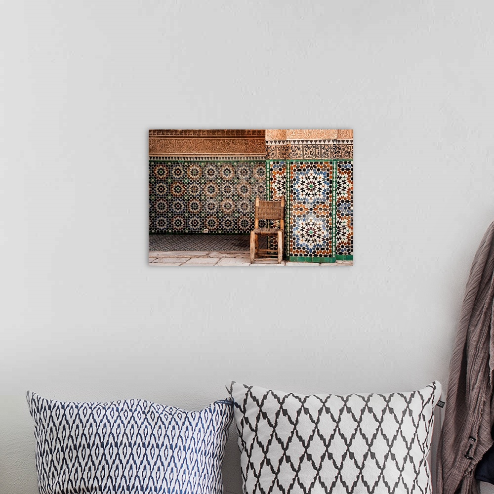 A bohemian room featuring Photograph of a wooden chair with a woven seat and back against beautifully tiled exterior walls.