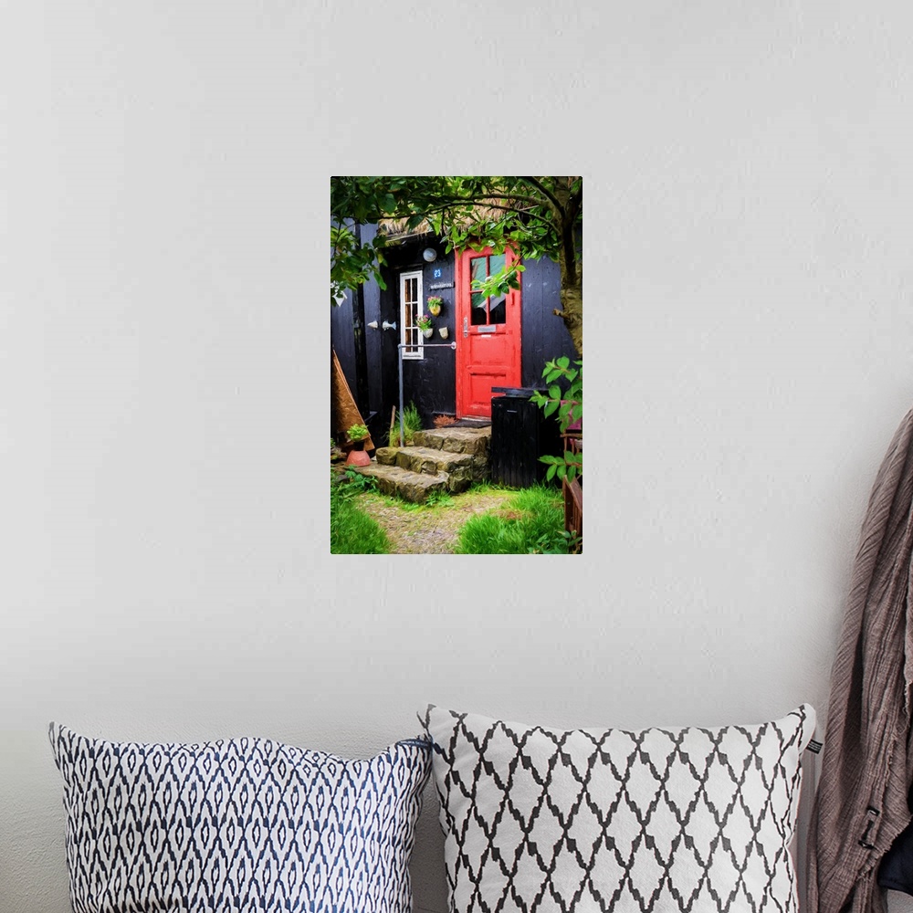 A bohemian room featuring A black painted house with a bright red door and stone steps.
