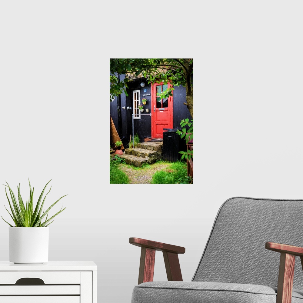 A modern room featuring A black painted house with a bright red door and stone steps.