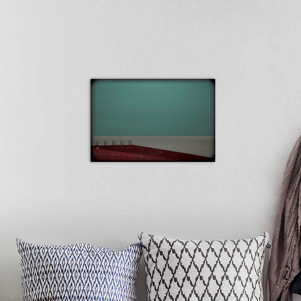 A bohemian room featuring Minimalist photograph of a red landing leading up to a calm, gray sea with a turquoise sky and da...
