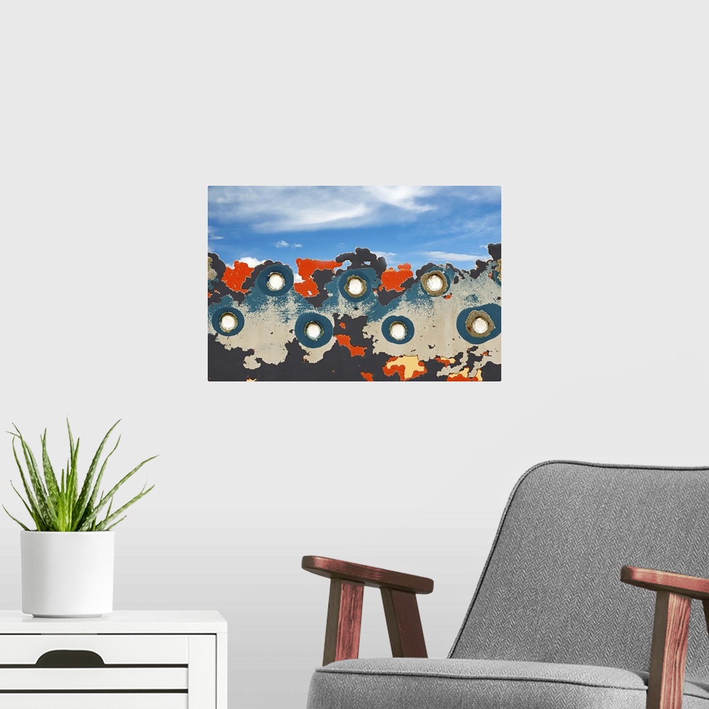 A modern room featuring Abstract image created by rivets and peeling paint against the blue sky.