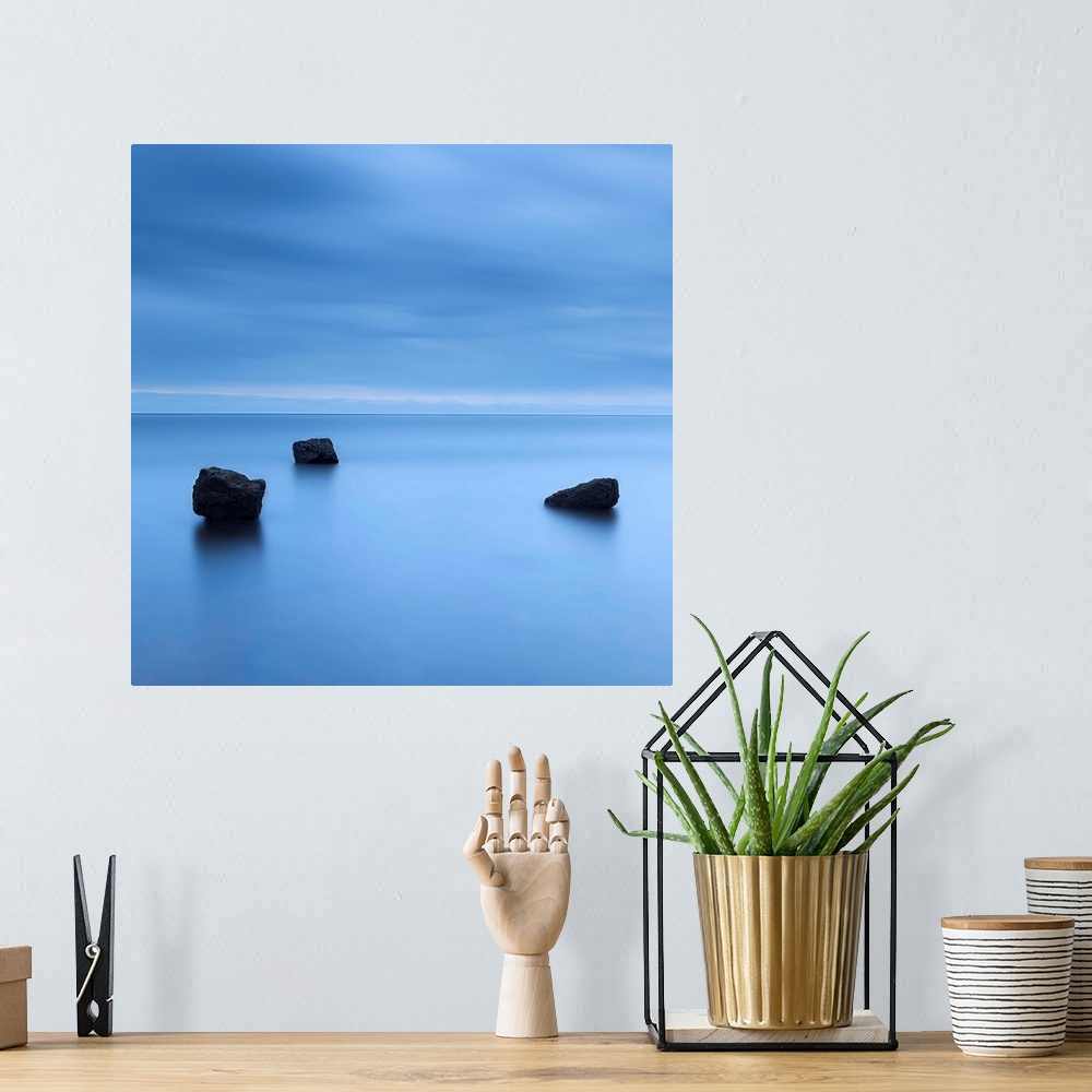 A bohemian room featuring A zen calm minimal minimalist cool deep blue image of three rocks in a flat calm sea.