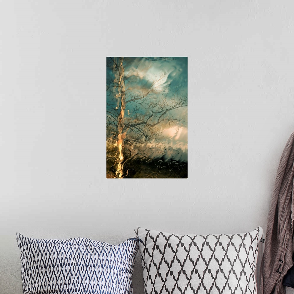 A bohemian room featuring Vertical, large wall picture of a big tree with bare branches on a hill below a sky of swirling, ...