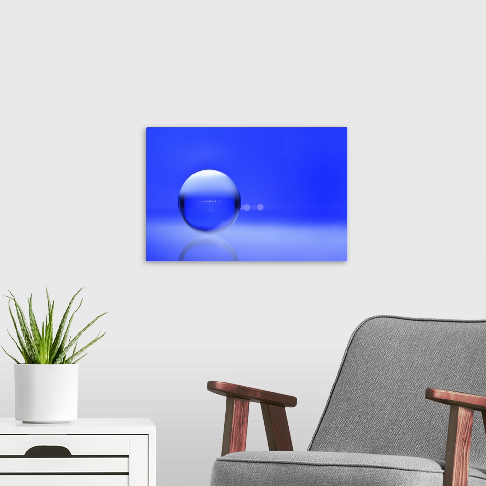 A modern room featuring A macro photograph of a water droplet on a blue surface.