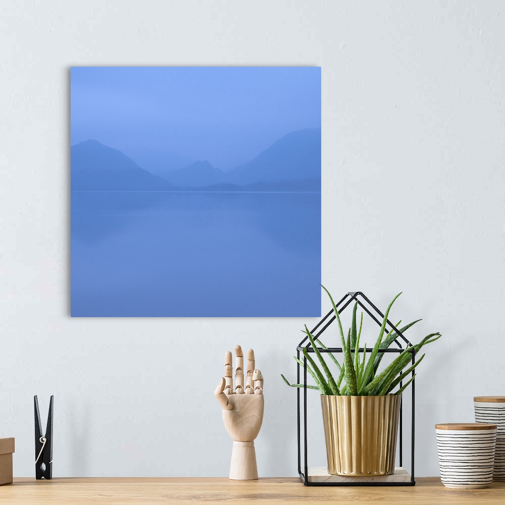 A bohemian room featuring Square photograph of a blue foggy lake with mountains in the background.
