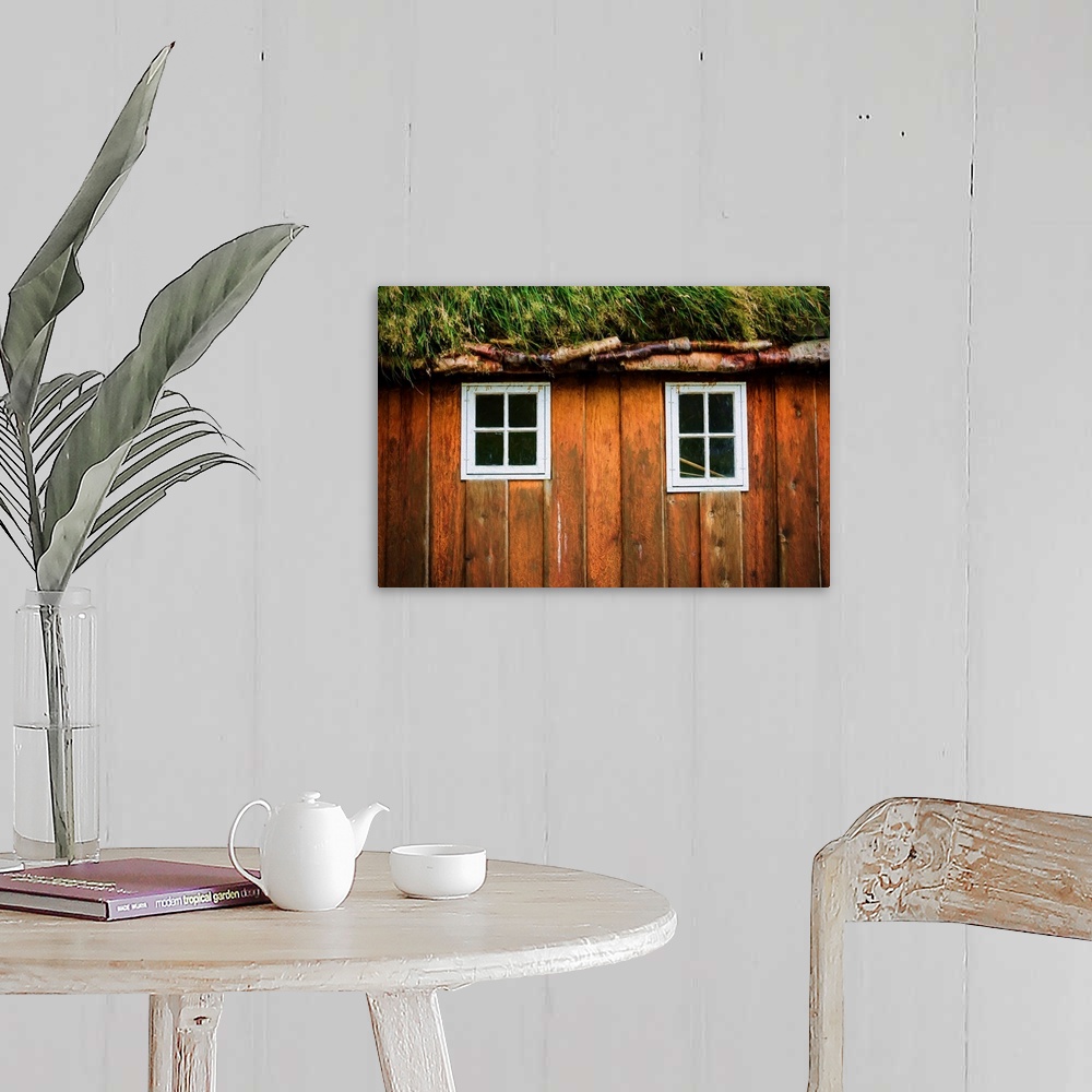 A farmhouse room featuring Two little windows in a wooden wall with a grassy roof.