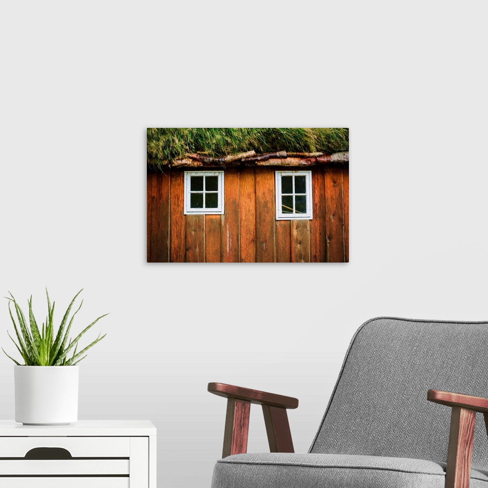 A modern room featuring Two little windows in a wooden wall with a grassy roof.
