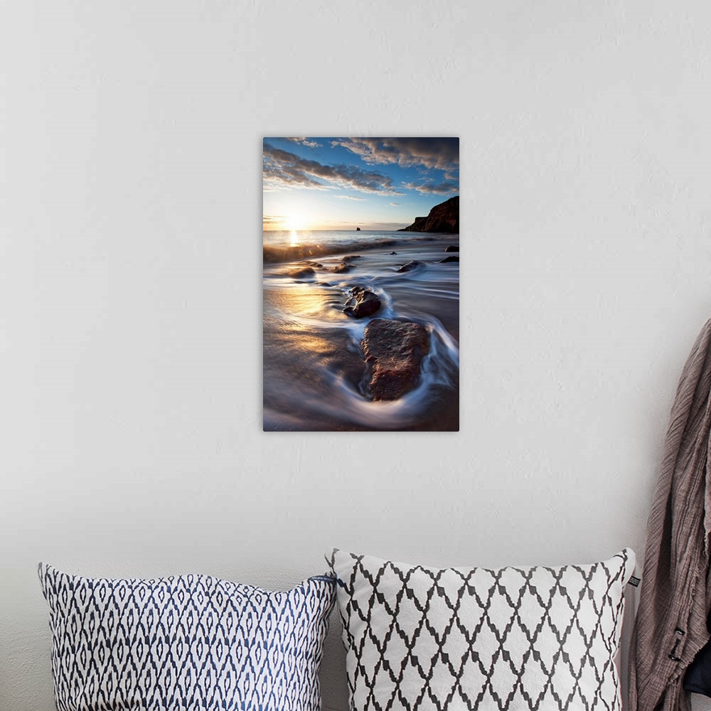 A bohemian room featuring Vertical photograph on a large canvas of the sun rising over waters rushing onto a rocky beach, i...