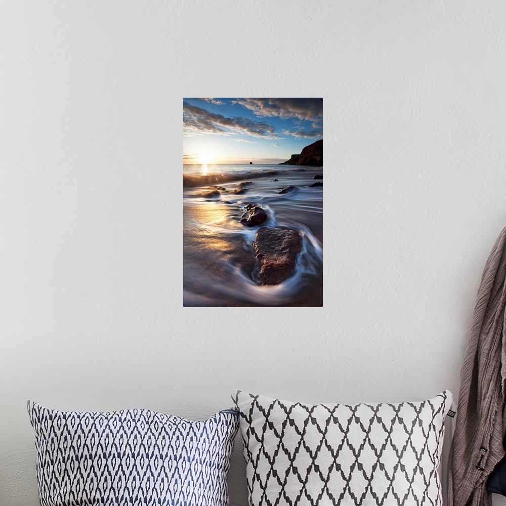 A bohemian room featuring Vertical photograph on a large canvas of the sun rising over waters rushing onto a rocky beach, i...